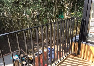 Simple black metal balcony with vertical bars.